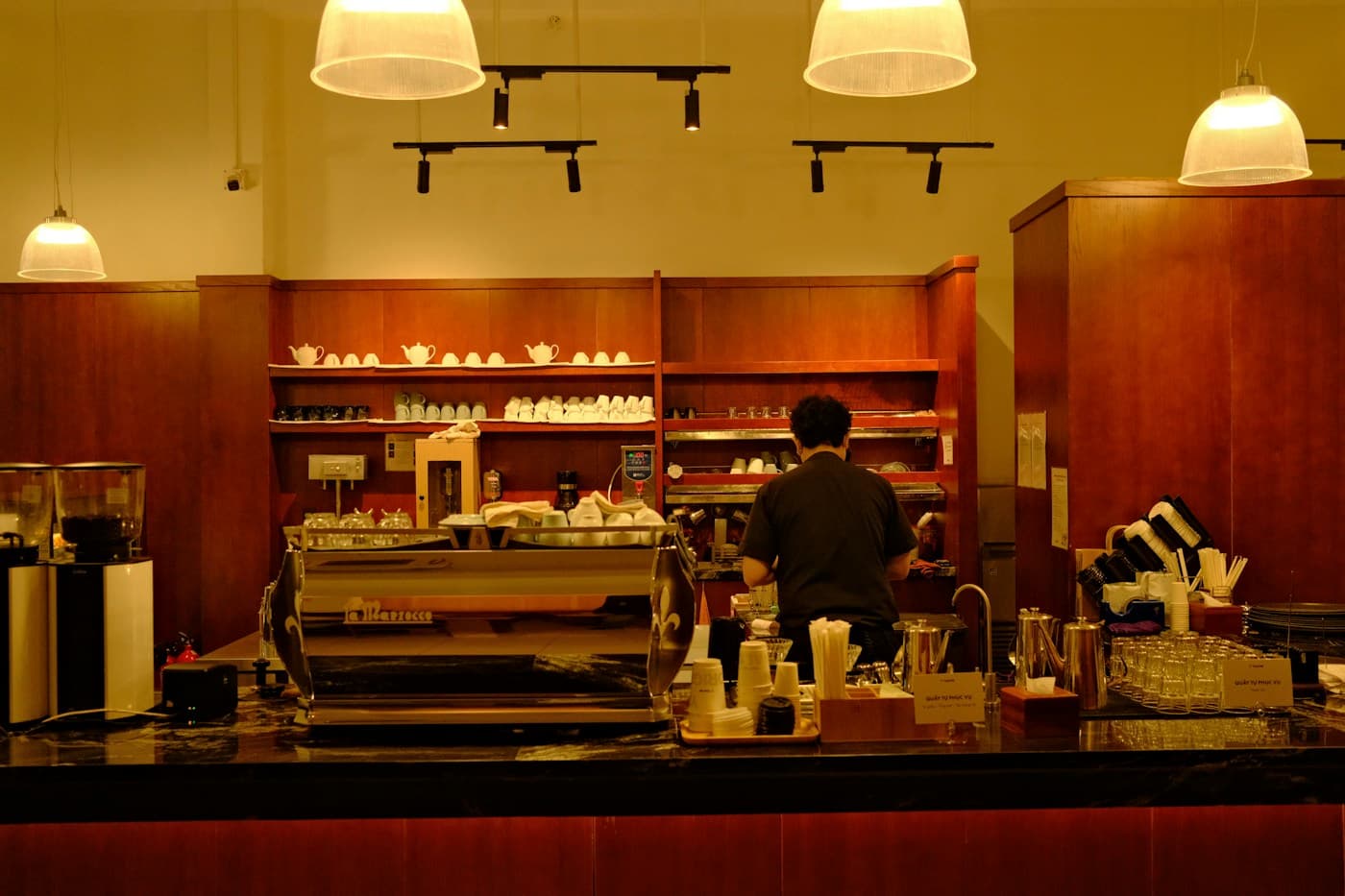 Una persona prepara café detrás de un mostrador de madera